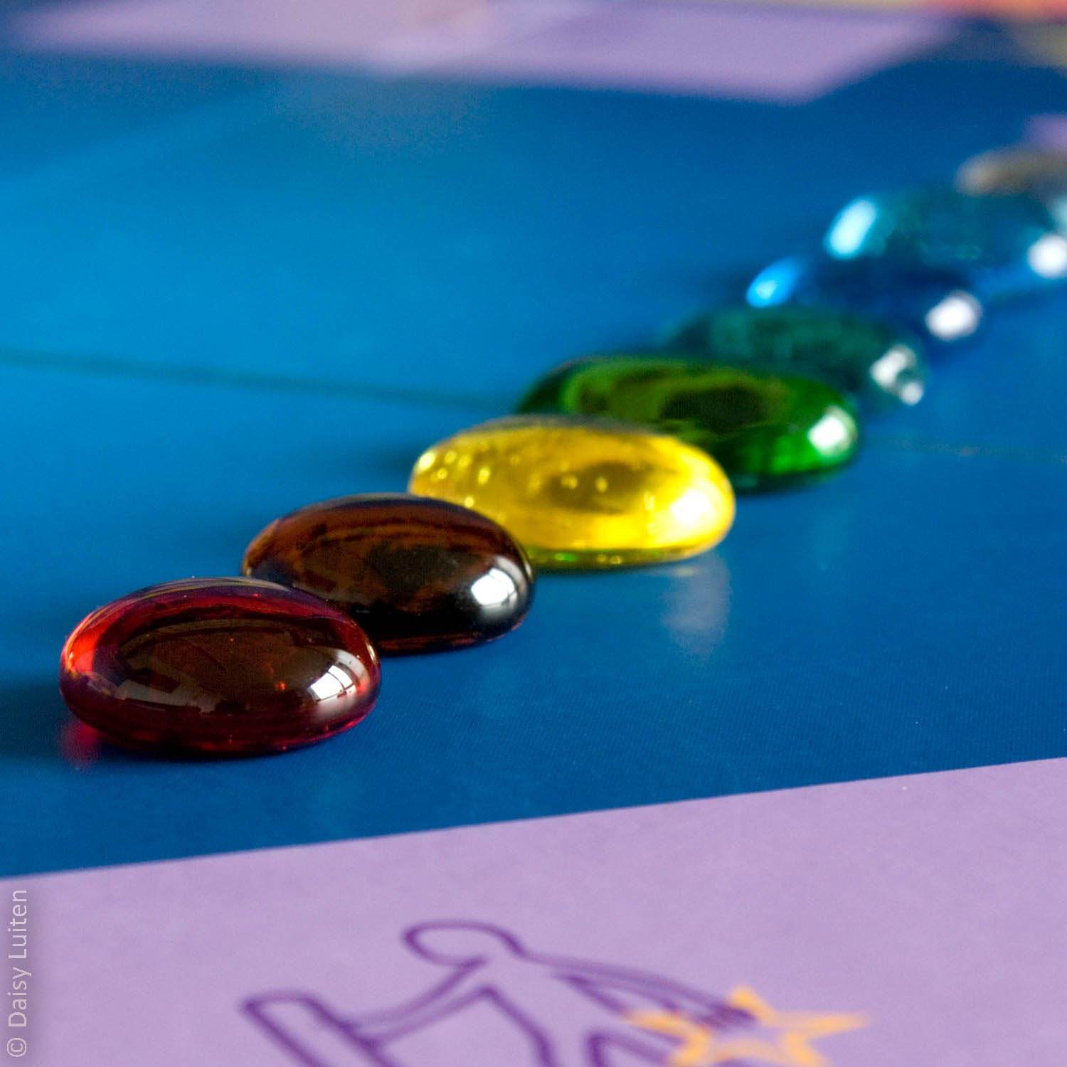 Glazen gekleurde tranen die parels worden als je je verhaal met elkaar deelt liggen in een rij op het blauwe spelbord.